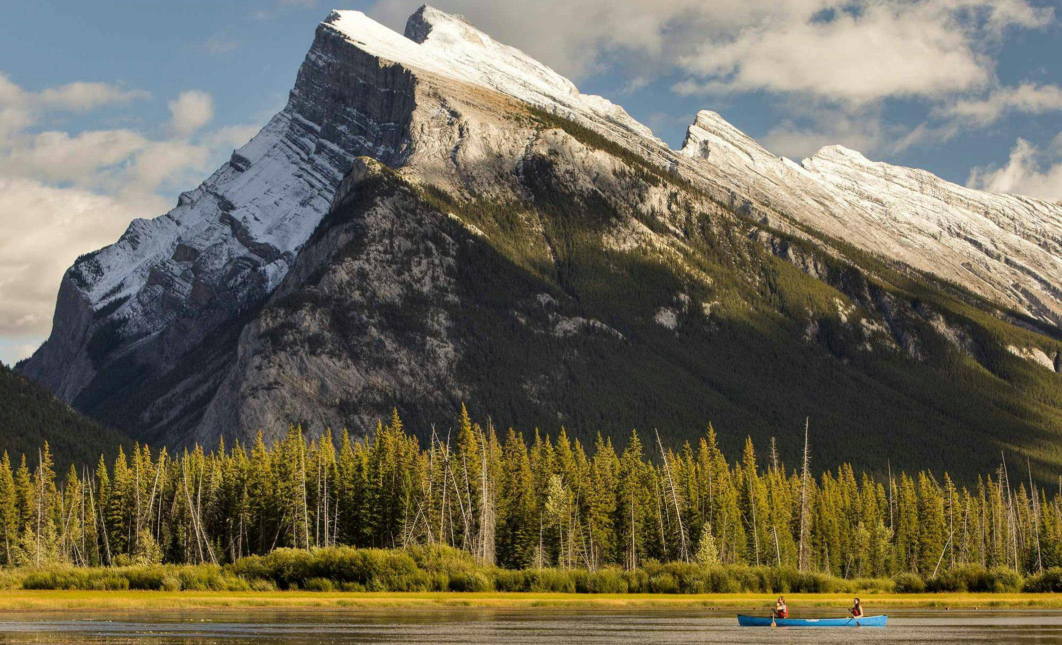 A canoe paddles along the waters of the Vermillion Lakes near Banff and Lake Louise, AB