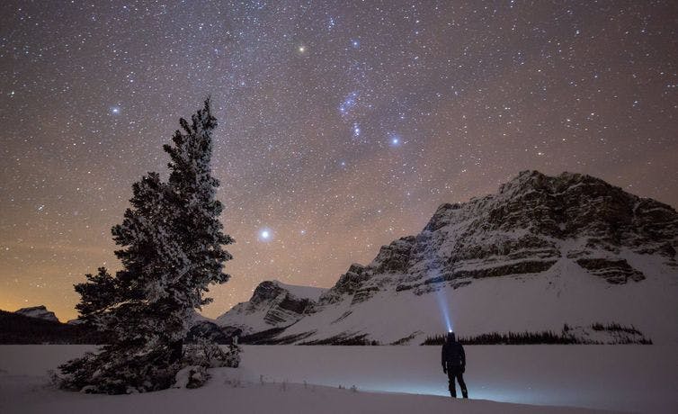 An onlooker takes in the outstandingly clear night skies of Lake Num Ti Jah, just off the Icefields Parkway in Banff National Park, AB.