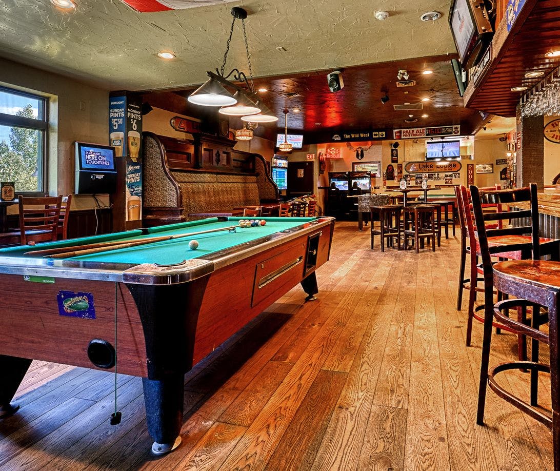 A pub interior including tables, a bar, and a pool table
