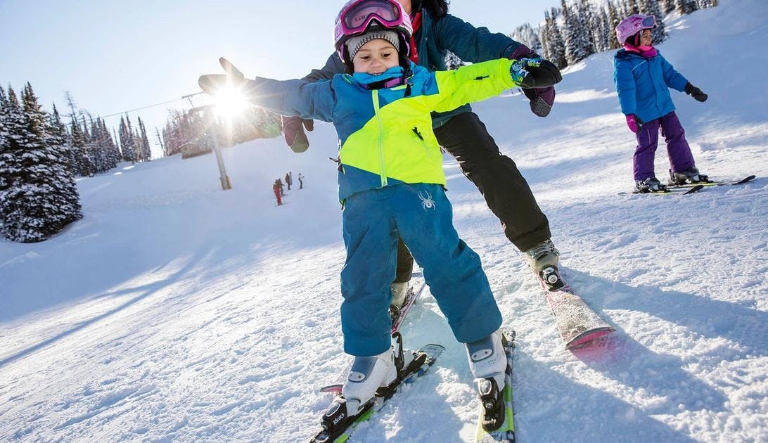 A little kid and their mom go downhill skiing at Banff Sunshine Village in Banff National Park.