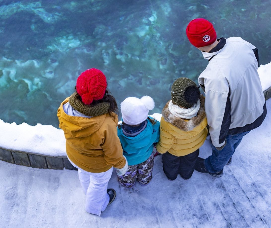 A family in their winter gear looking into the basin at the Cave &amp; Basin