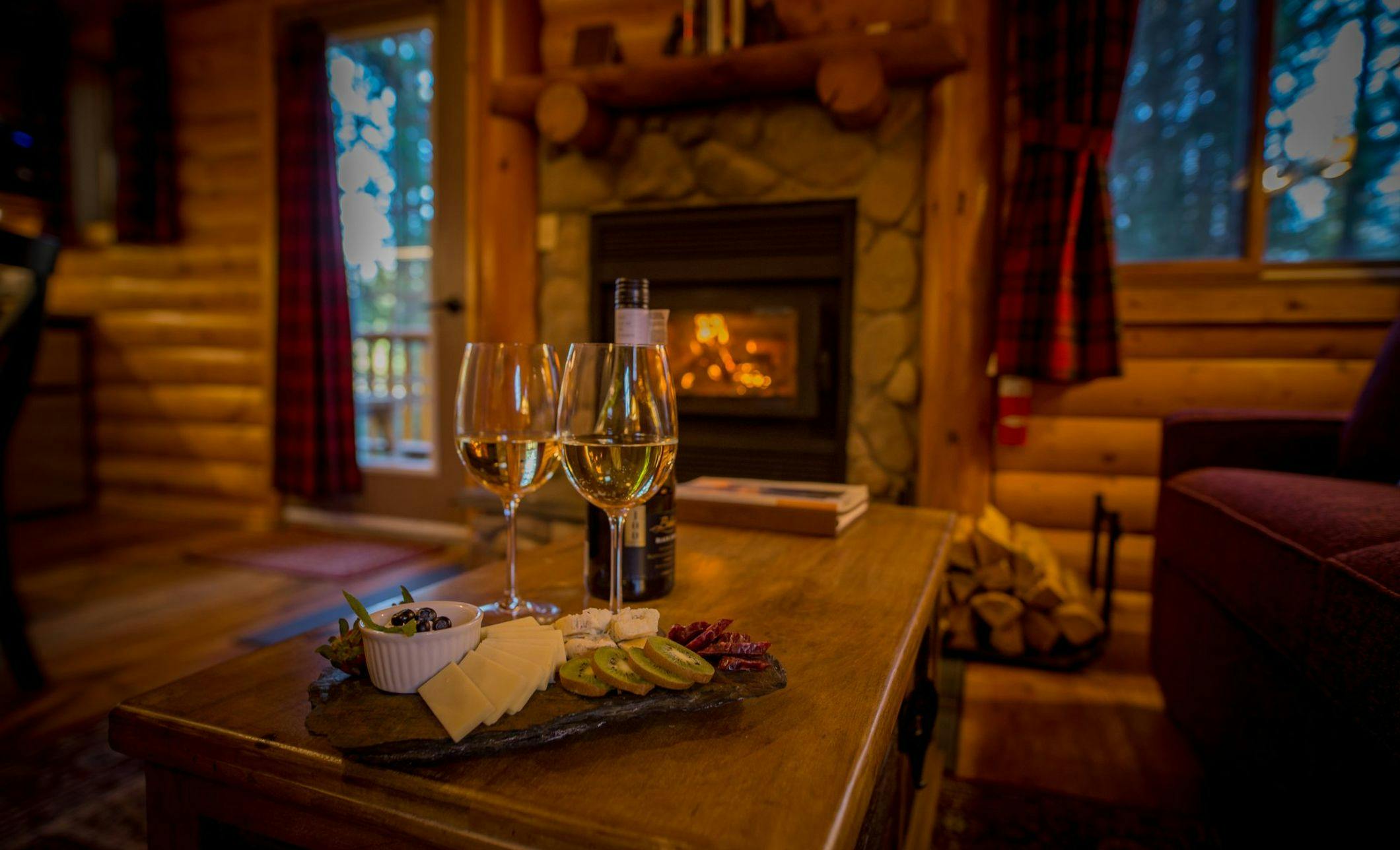 Wine glasses and charcuterie board by fireplace in a cozy cabin