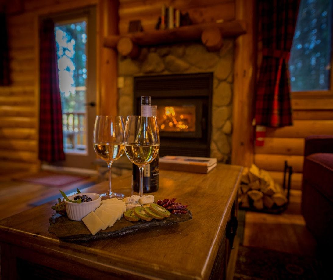 Wine glasses and charcuterie board by fireplace in a cozy cabin
