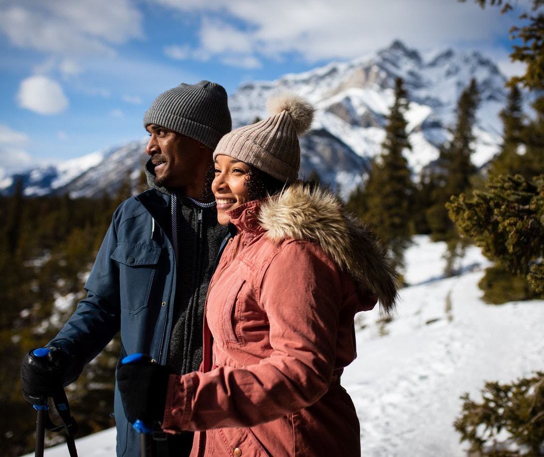 A couple stops to look at the view while enjoying a winter hike on snowy trails on a bright blue day