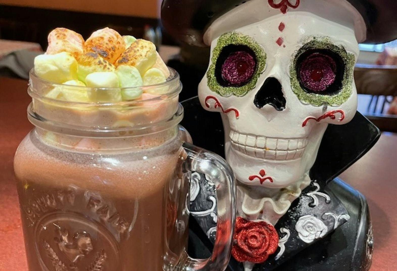 A hot chocolate with marshmallows beside a Dia de los Muertos statue at Tooloulou's in Banff. 