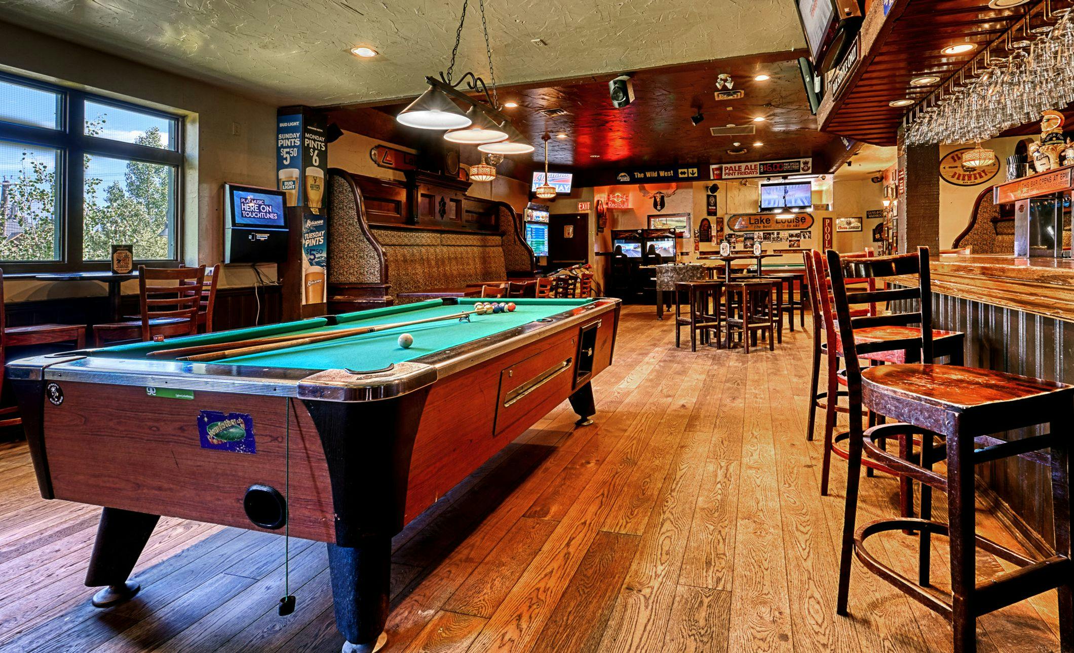 A pub interior including tables, a bar, and a pool table
