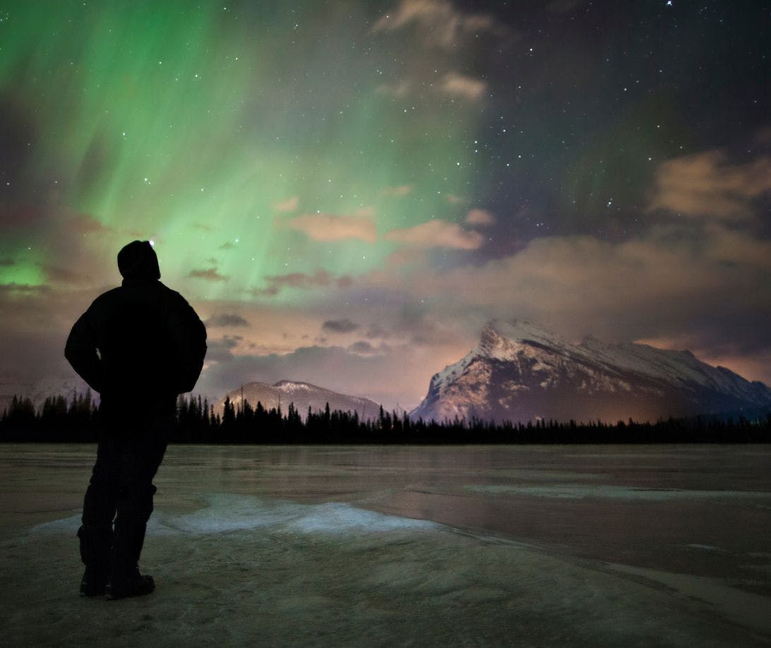 A man watches the Northern Lights above the skies of Banff and Lake Louise