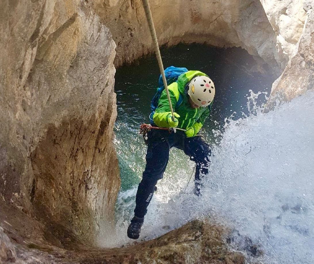 Guide rappels down a waterfall into a canyon