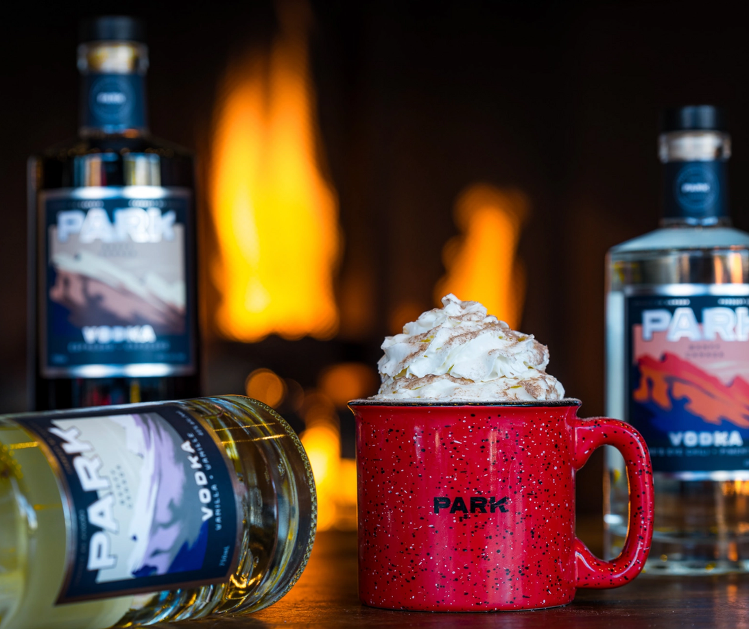 A hot chocolate in a red cup with a fire behind it at Park Distillery in Banff. 
