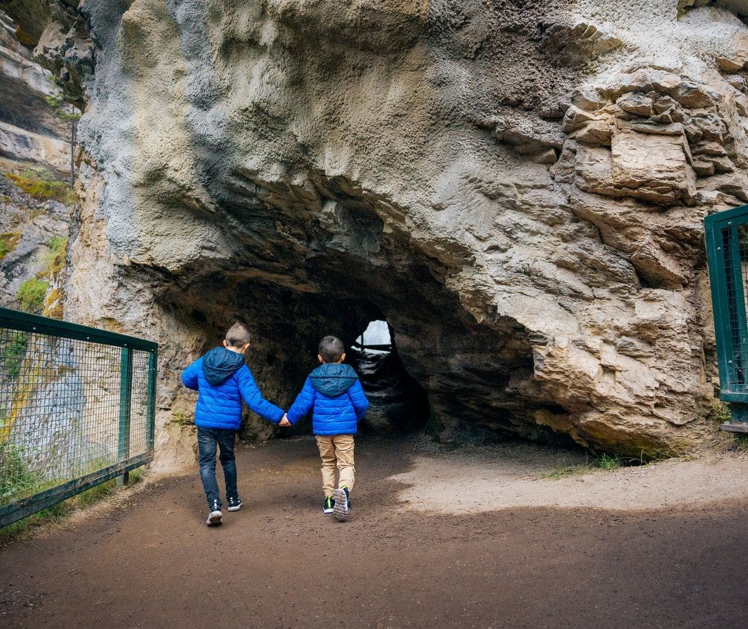Two young boys heading into a cave in Johnston Canyon while hiking