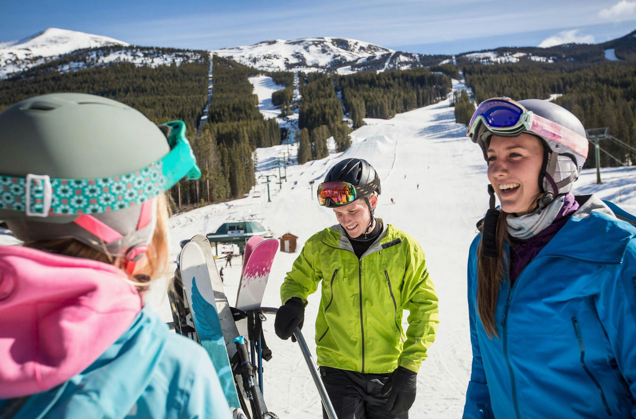 Three people laughing at the bottom of a ski and snowboard run in Banff National Park