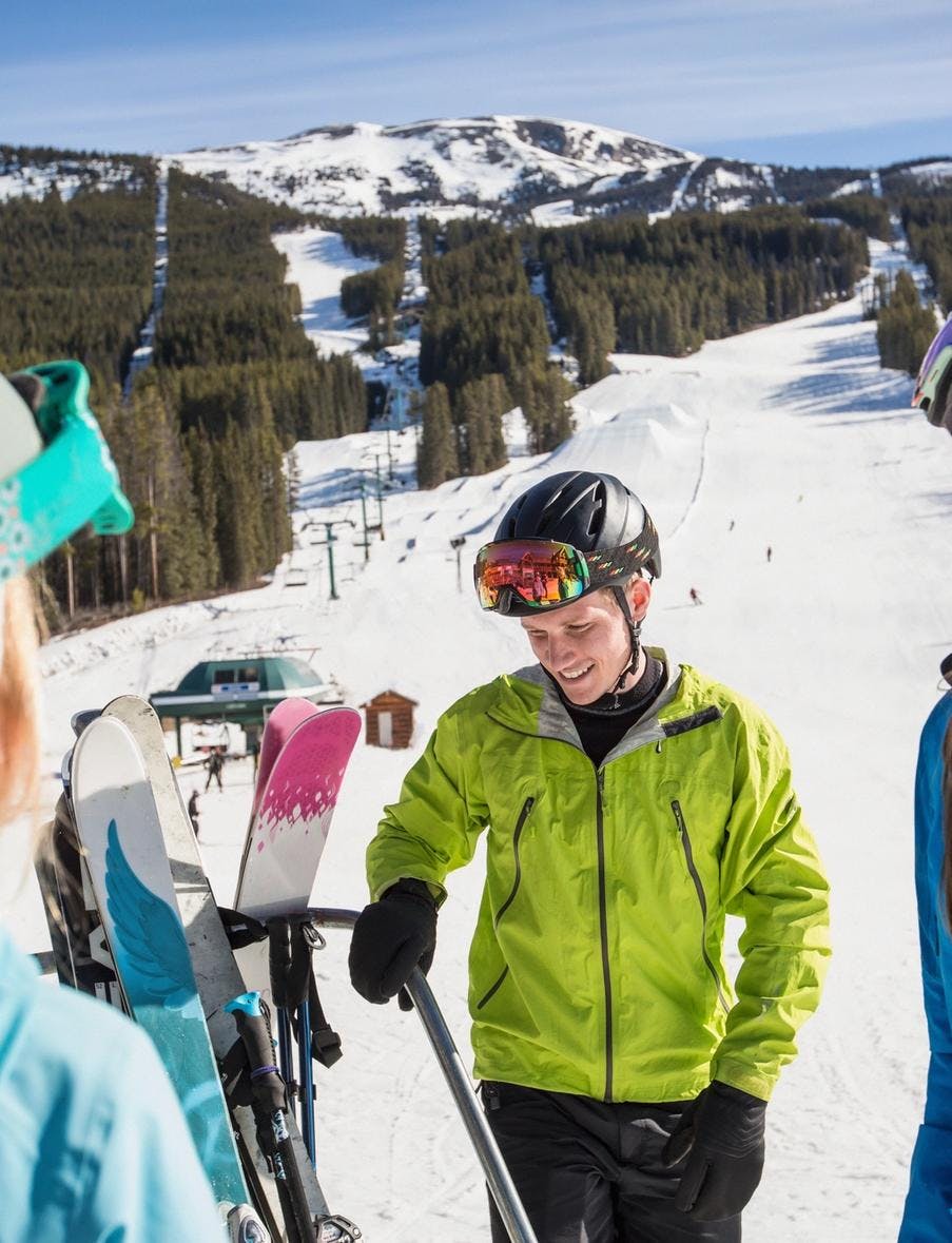 Three people laughing at the bottom of a ski and snowboard run in Banff National Park