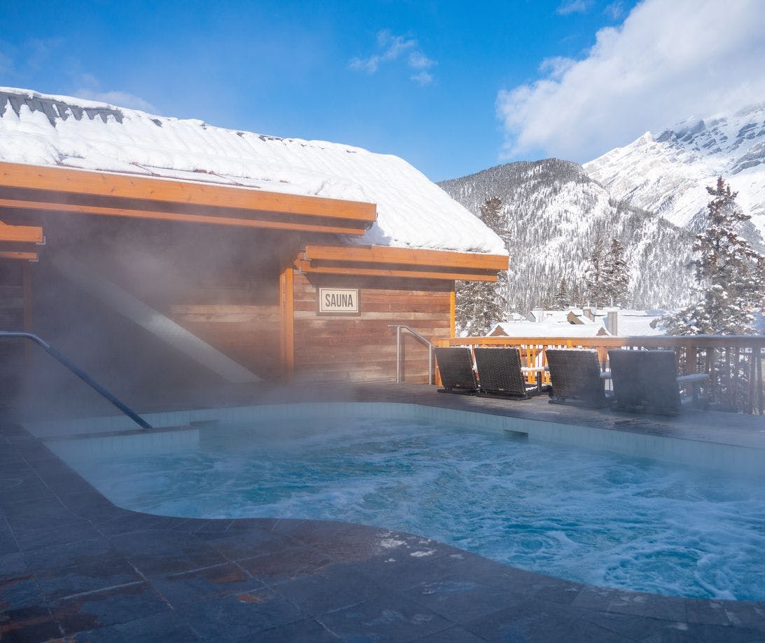 A rooftop hot tub and sauna with snowy mountains in the background