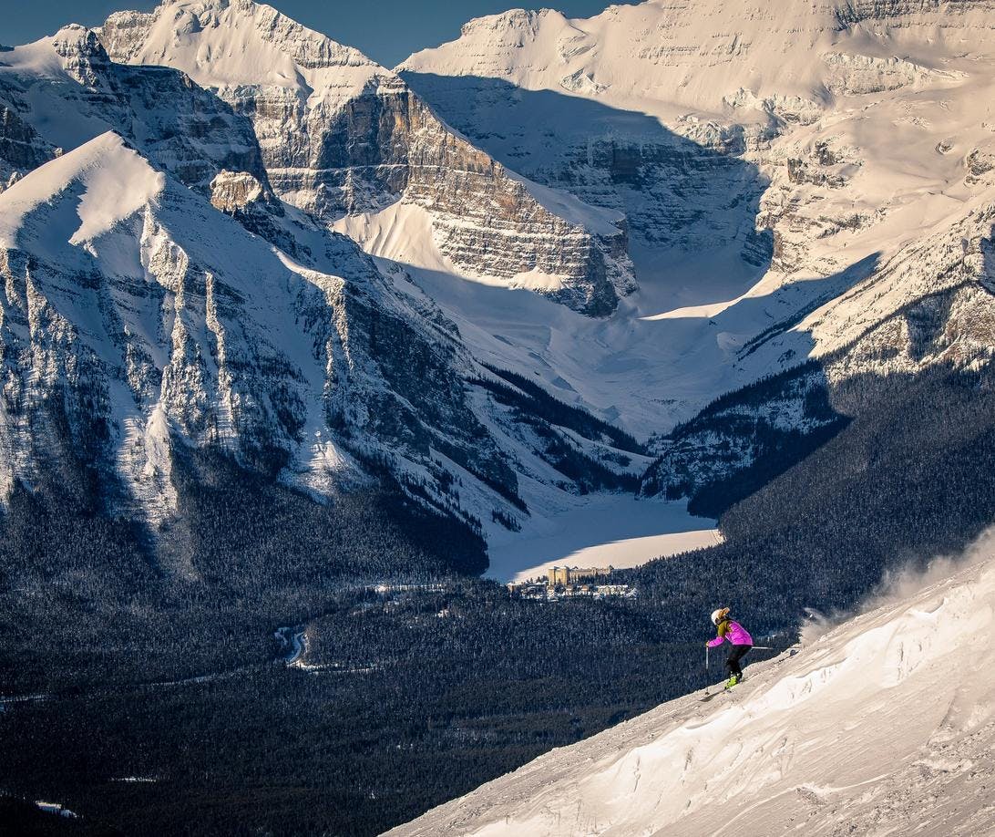 Downhill skier on Lake Louise Ski Resort with Chateau Lake Louise in the background.