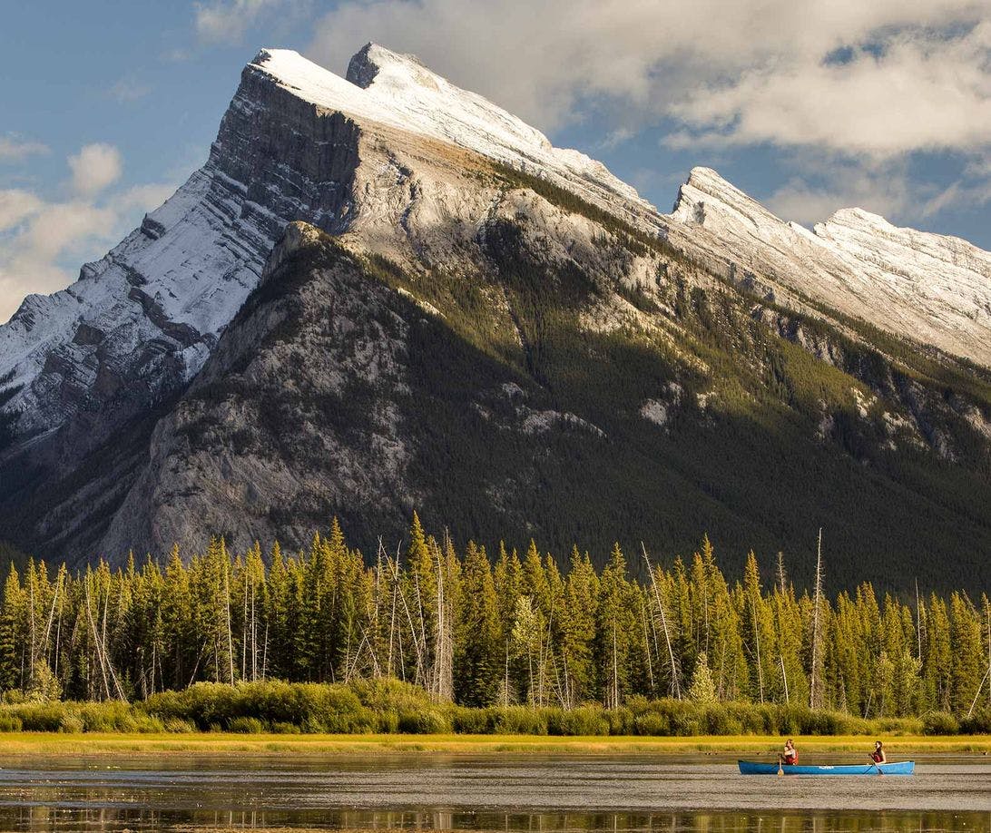 A canoe paddles along the waters of the Vermillion Lakes near Banff and Lake Louise, AB