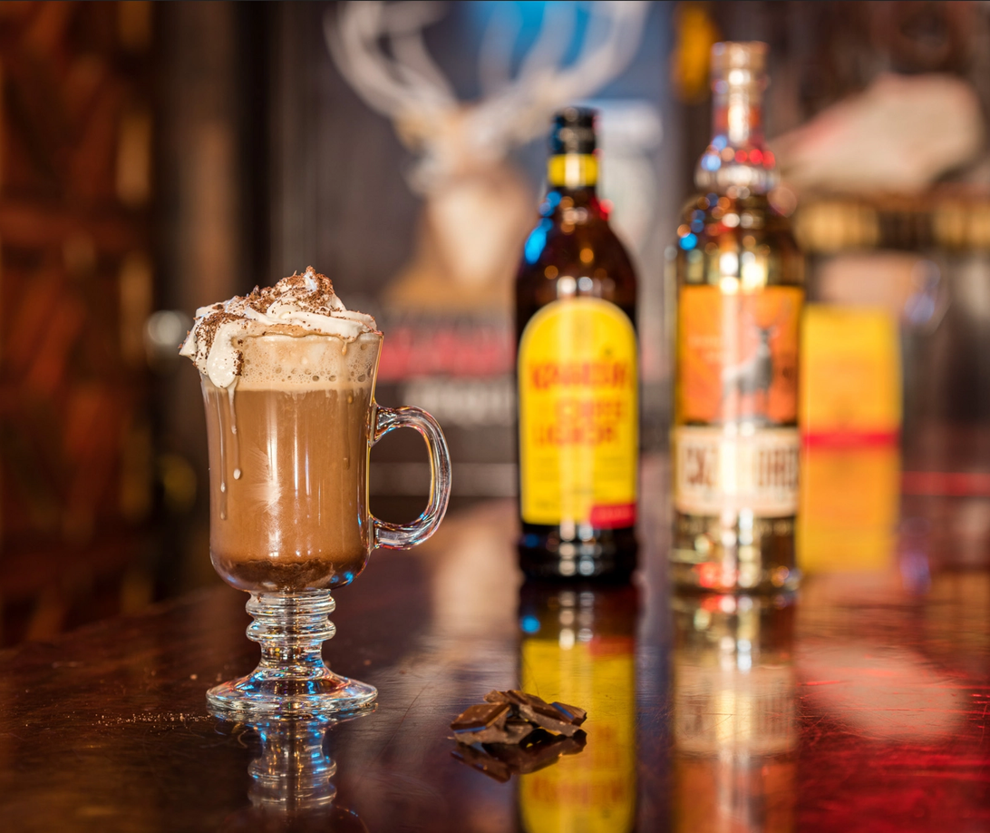 A hot chocolate on the table with liquor bottles on the table at Magpie & Stump.