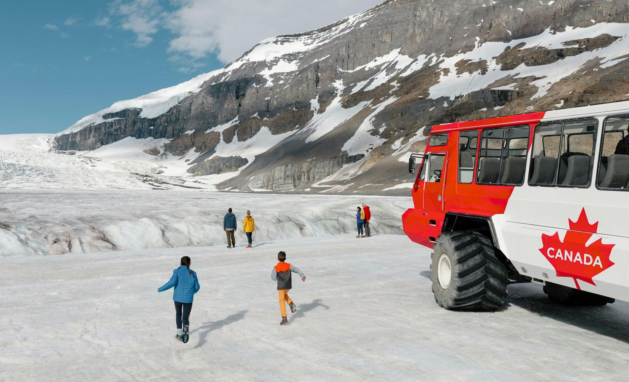 A family walks on the Athabasca Glacier after taking the Ice Explorer bus pictured on the right to reach it at the Columbia Icefield near Banff National Park.