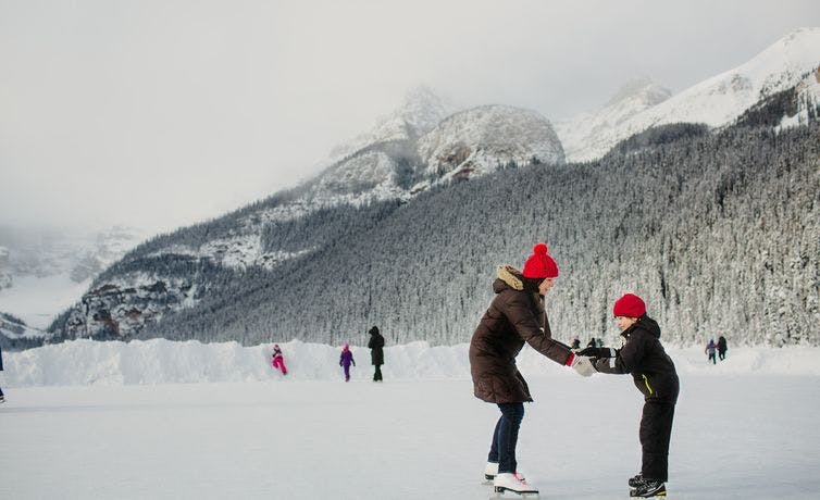 A mother and child ice skate on Lake Louise, Banff National Park, AB