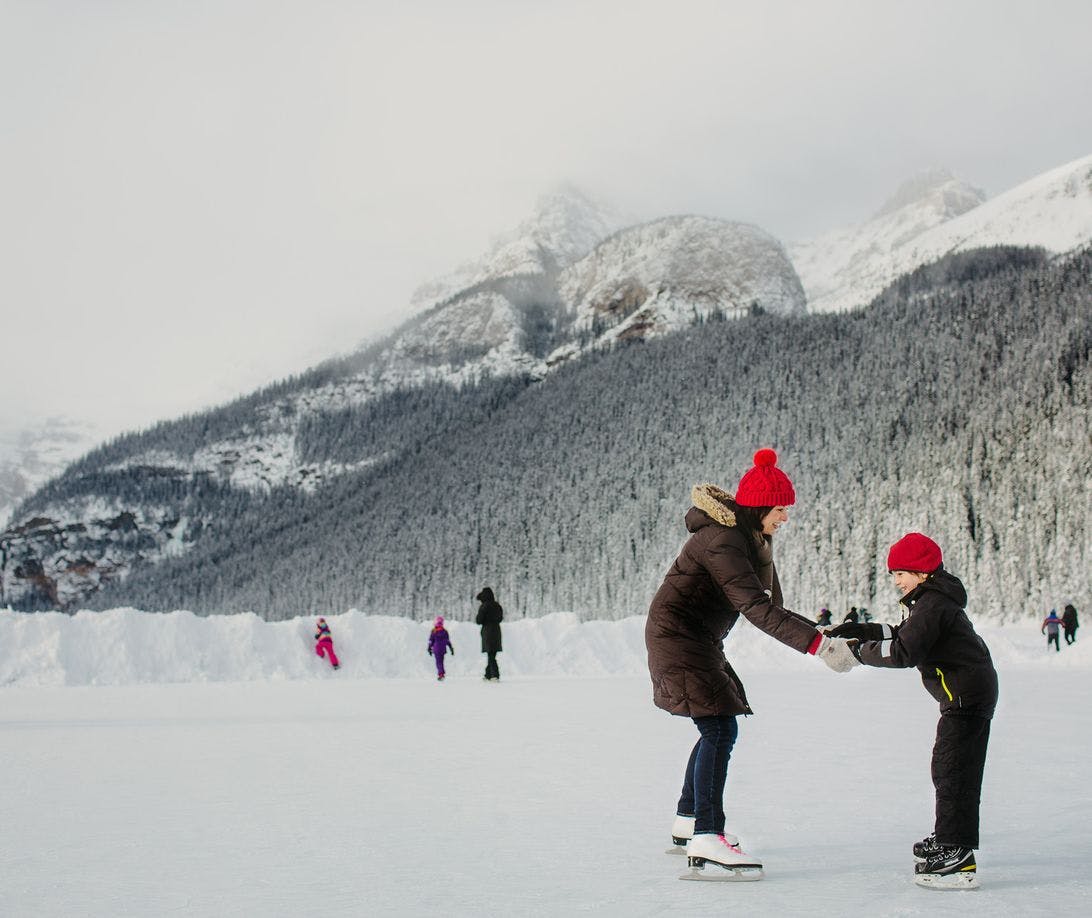 A mother and child ice skate on Lake Louise, Banff National Park, AB