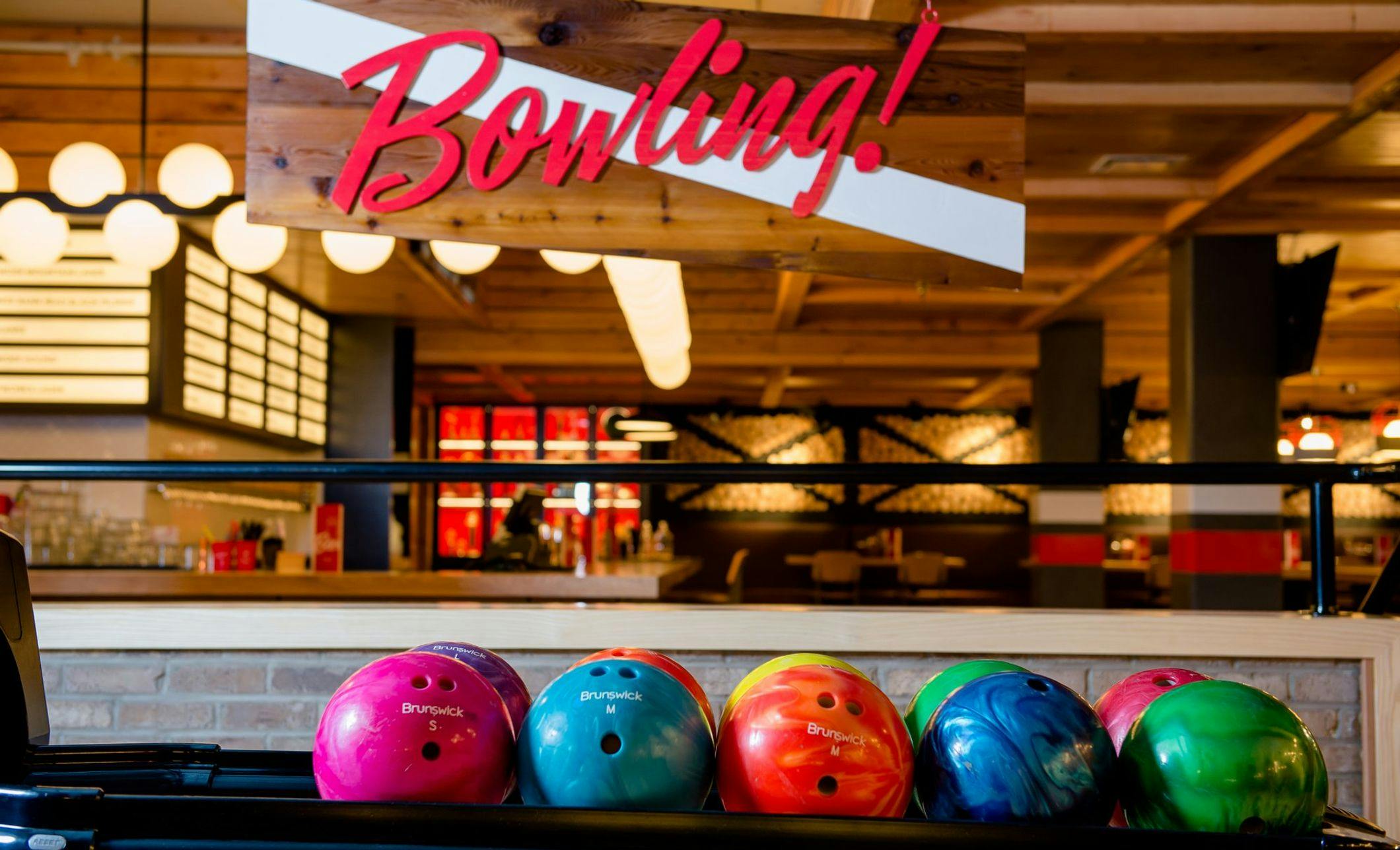 A bowling sign in the background with colourful bowling balls in the foreground