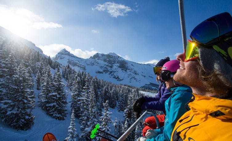 A group of friends soaks in the spring sun while riding the chairlift in Banff National Park, AB