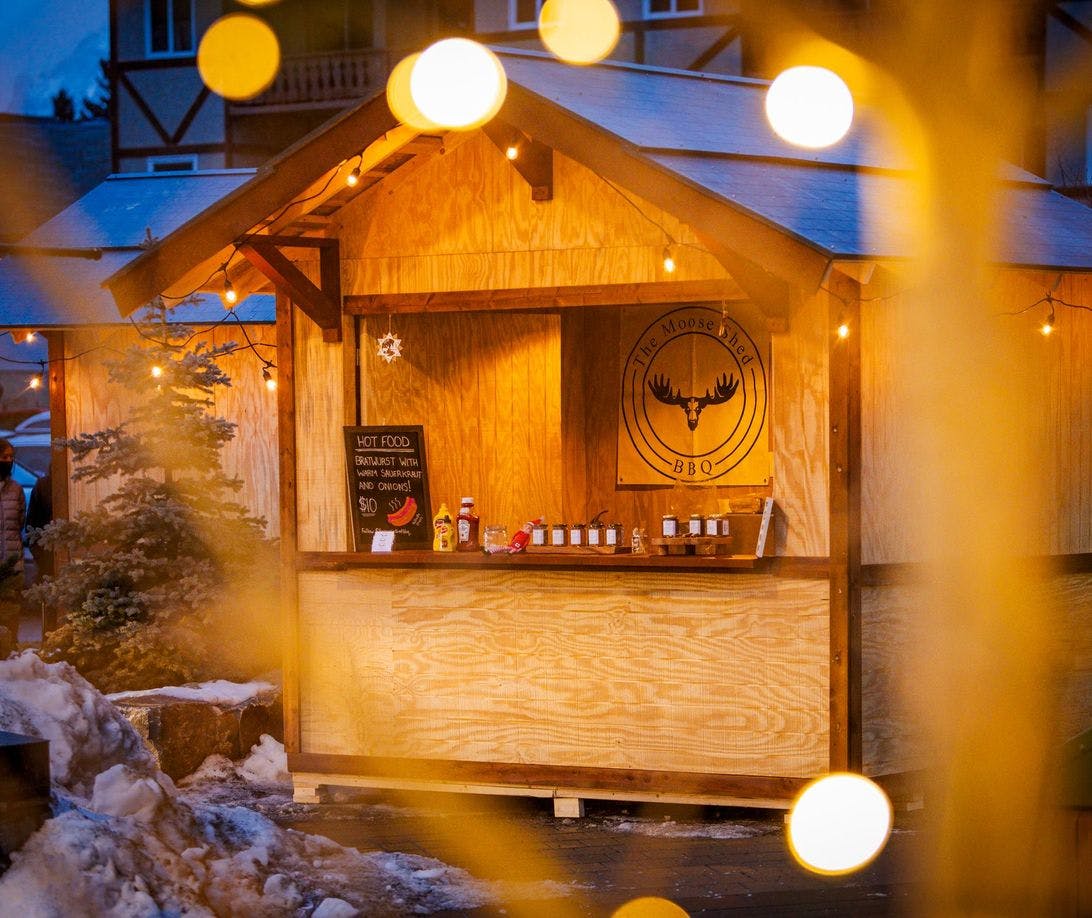 A market hut decorated and framed in Christmas lights on a snowy winter evening