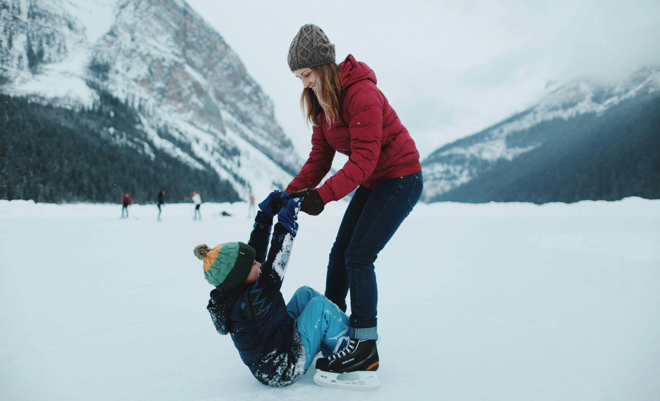 A mother helps her son to ice skate on Lake Louise, AB