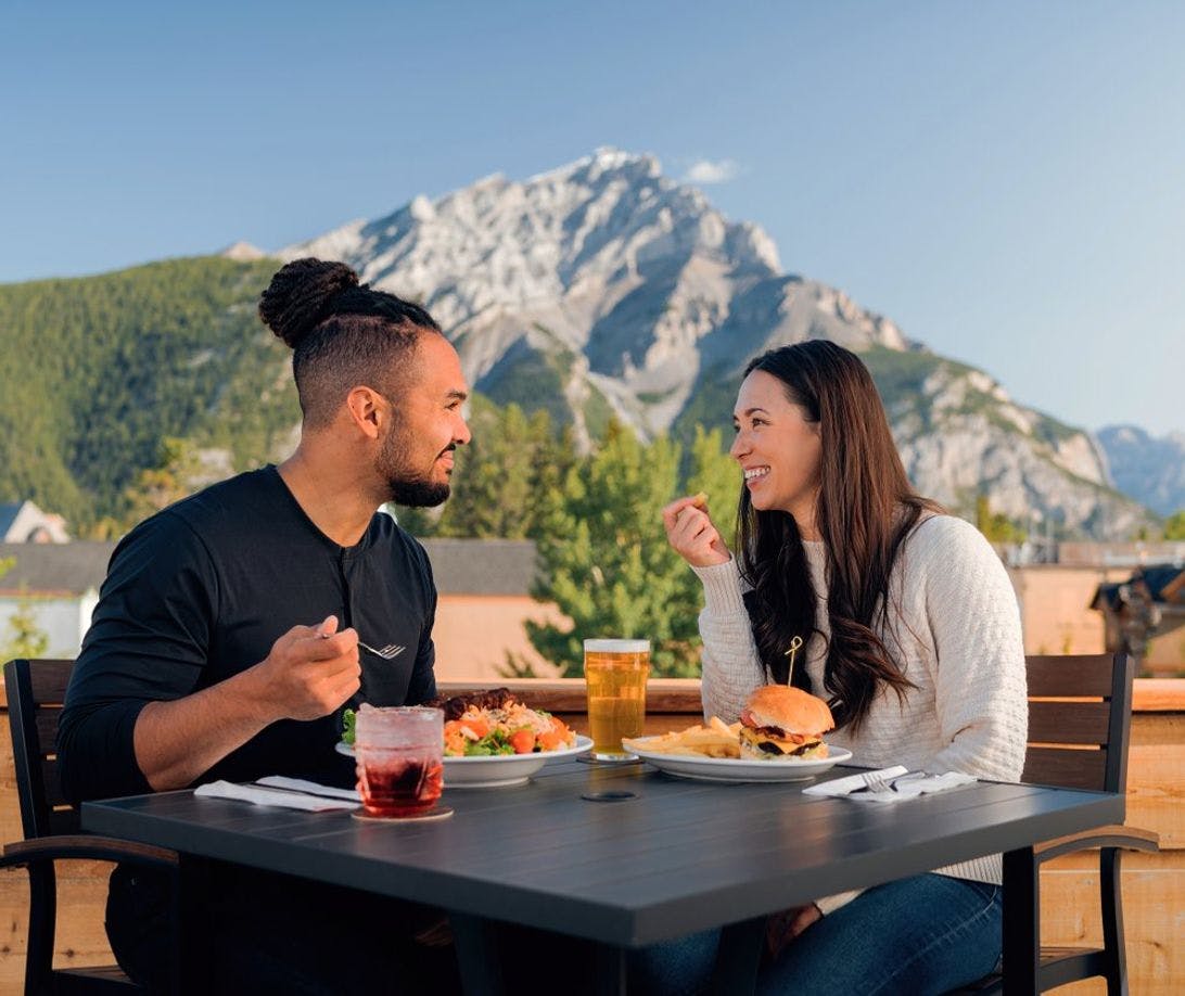 Two people enjoy a patio in Banff in Banff National Park in the Canadian Rockies.