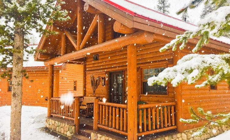 Snow falling around a wooden cabin