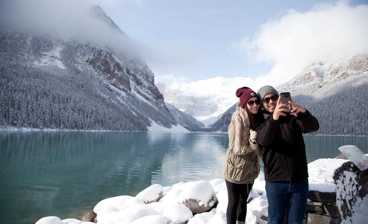 A couple takes a selfie at Lake Louise in the winter in Banff National Park.