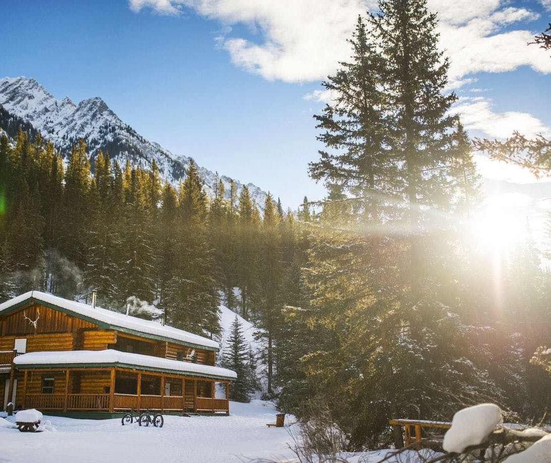 A wooden backcountry lodge on a sunny winter day