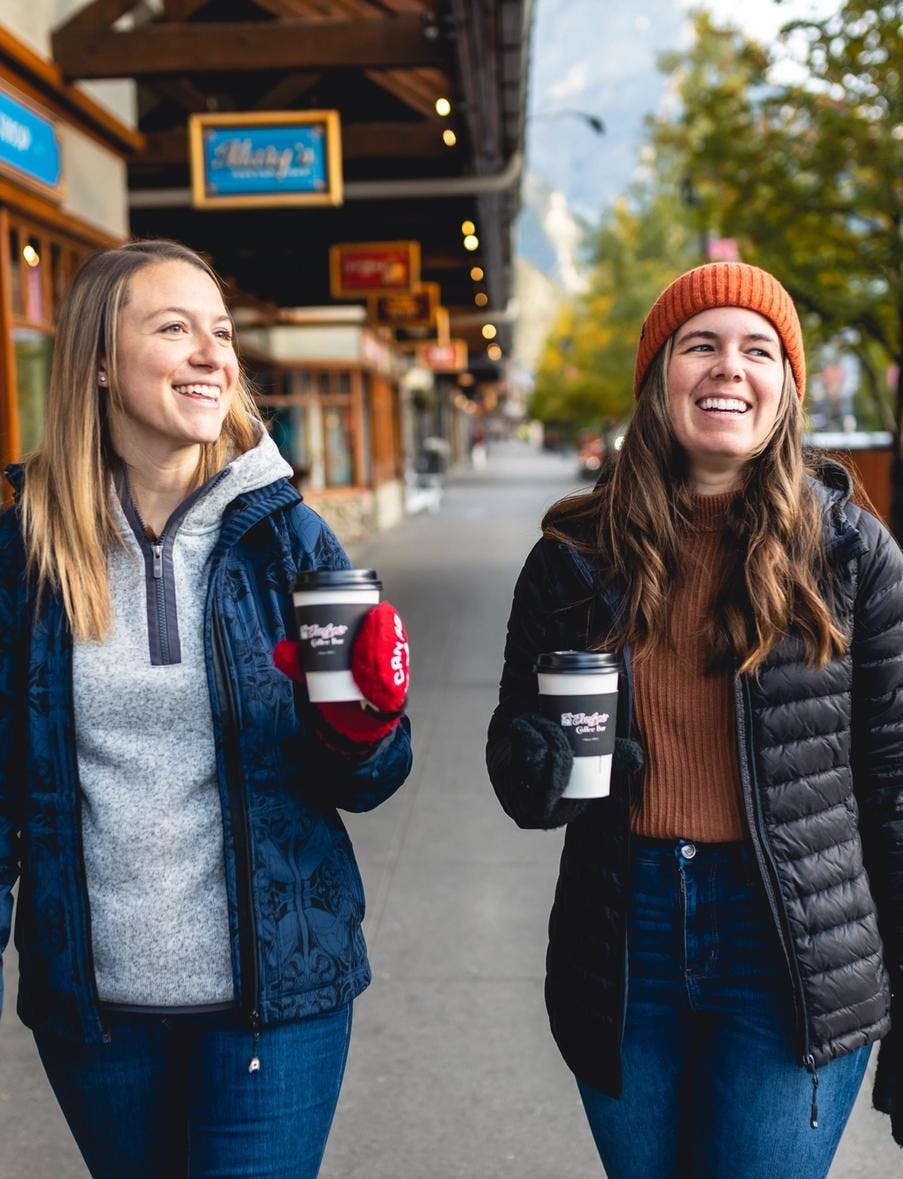 Two women drink coffee on Banff Ave in Banff, Canada.