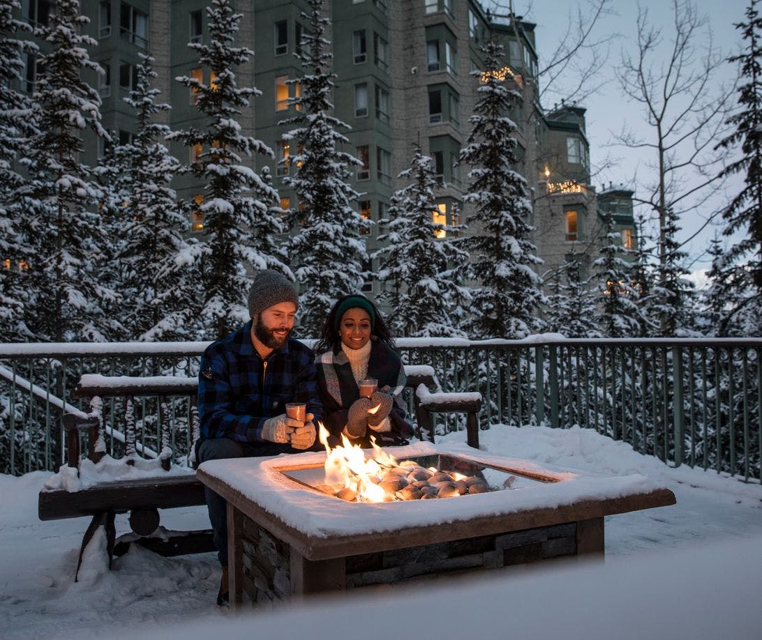 Couple drinking hot chocolate by a warm fire at the Rimrock Hotel in Banff National Park