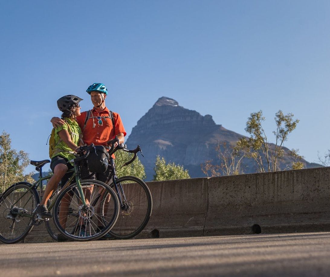 Two cyclists take a photo while riding the Bow Valley Parkway in Banff National Park.