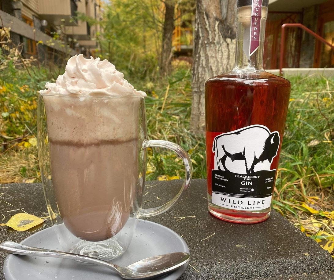 A hot chocolate outside beside a bottle of gin from the Meatball in Banff.