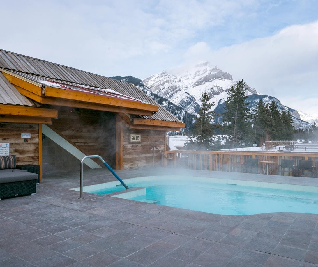 Rooftop Hot Tub &amp; Lounge Area with Snow-Capped Mountain Peak in the Background