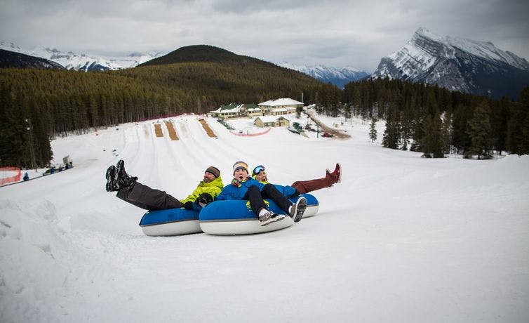 A family tubes on the snowy slopes of Banff and Lake Louise, AB