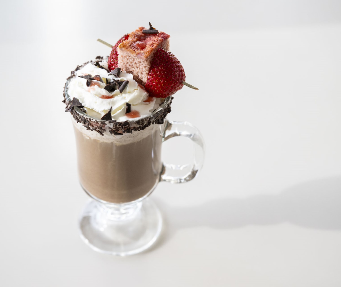 A hot chocolate with a strawberry on a white backdrop at Maclab Bistro in Banff.
