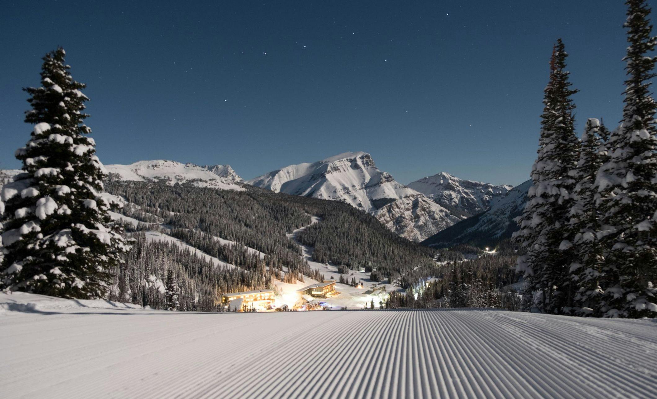 Sunshine Village Ski Resort lit up at night with snow on the ground and stars in the sky