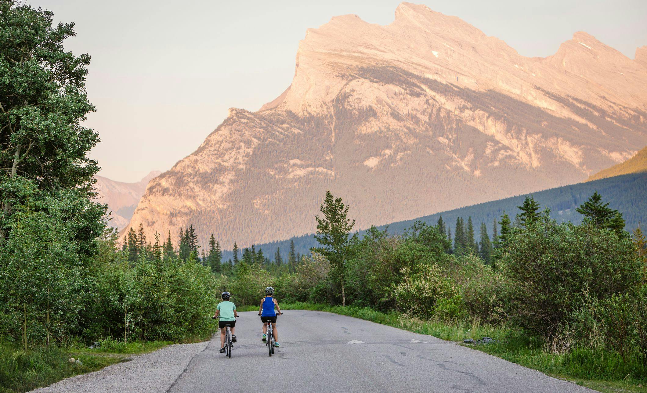 Two cyclists ride their bikes down Vermilion Lakes Road.