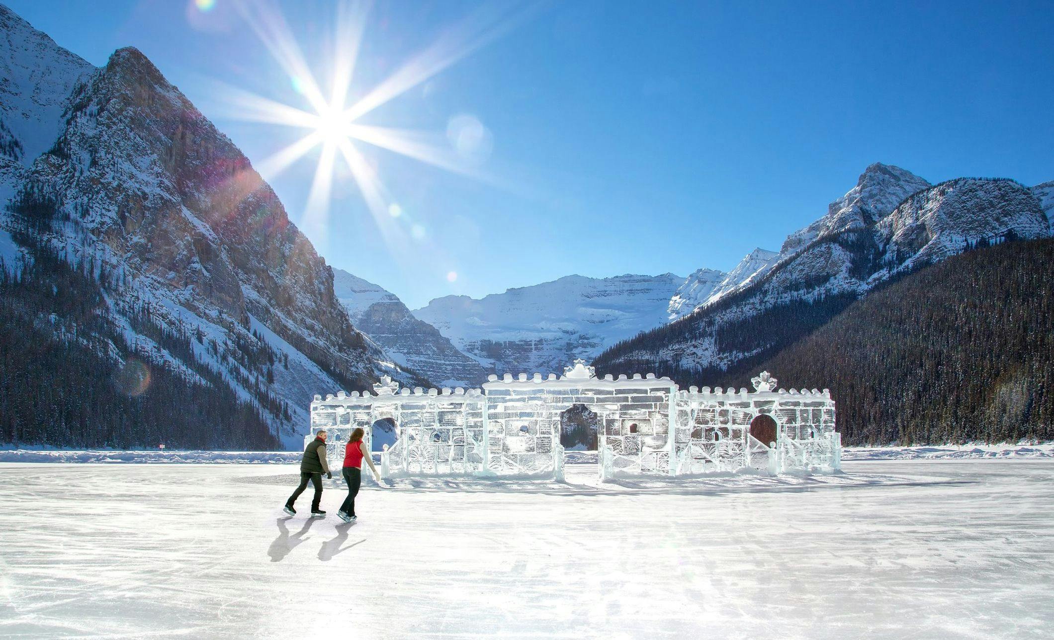 A couple skating towards an ice castle on the frozen Lake Louise