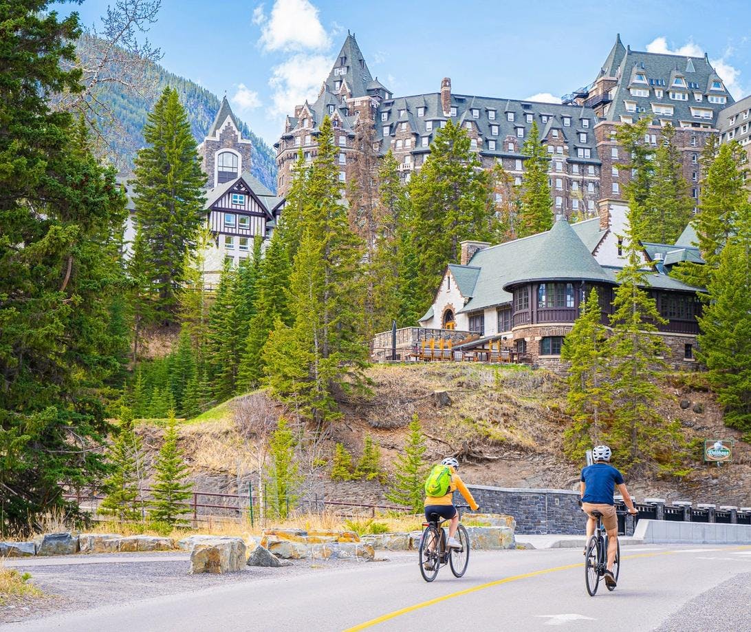 Couple Biking towards Fairmont Banff Springs Hotel